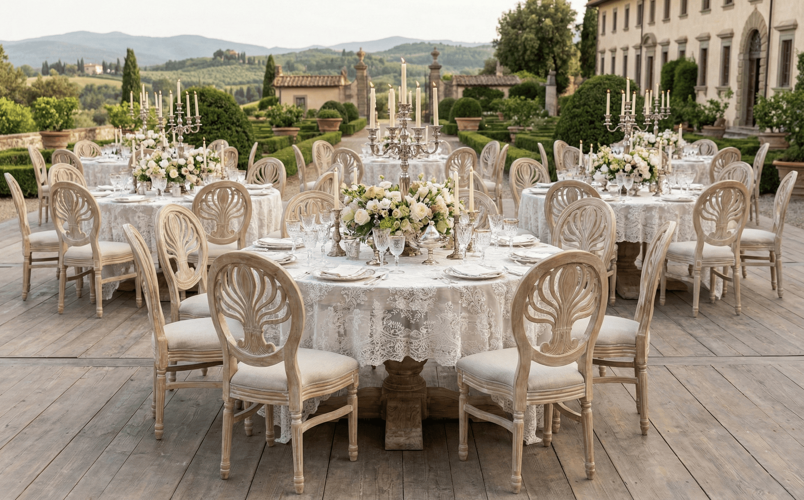 Elegant wedding table setup with high-end furniture, floral centerpieces, and ornate candelabras in an outdoor estate setting.